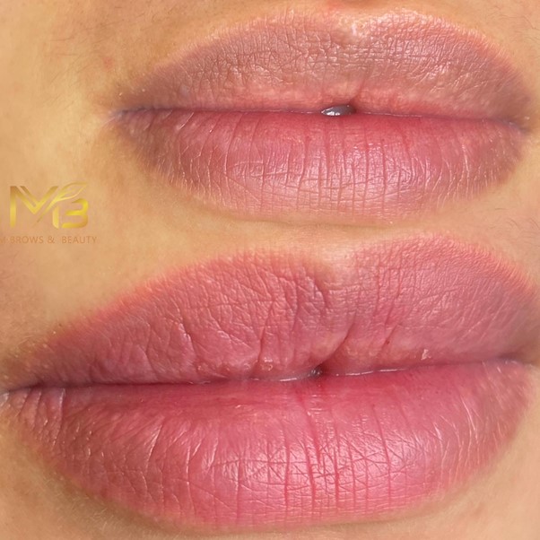 M Brows and Beauty Close-up of lips showing a "before and after" comparison of lip pigmentation treatment; the top lip appears more even-toned and vibrant than the bottom. A faint beauty business logo is visible on the left.